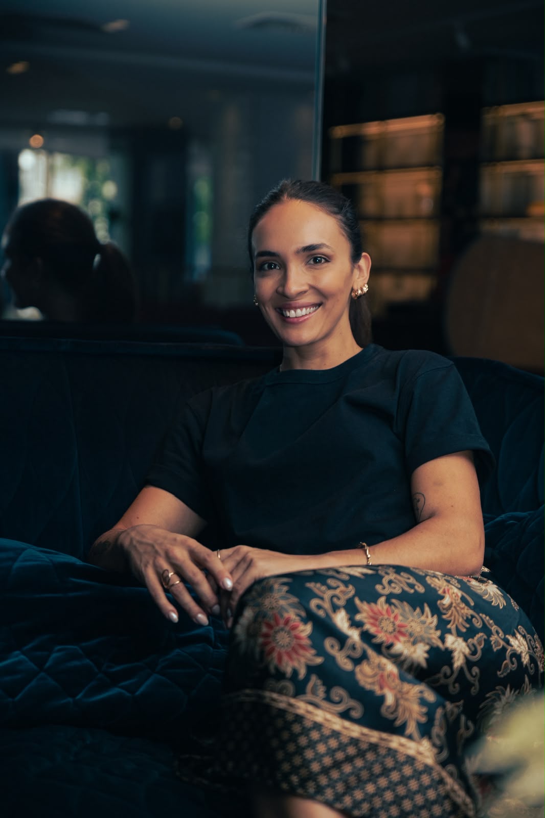Beatriz Schutz sentada em um sofá azul, sorrindo
